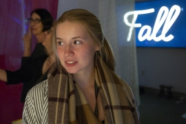A woman lighted by a neon "fall" sign